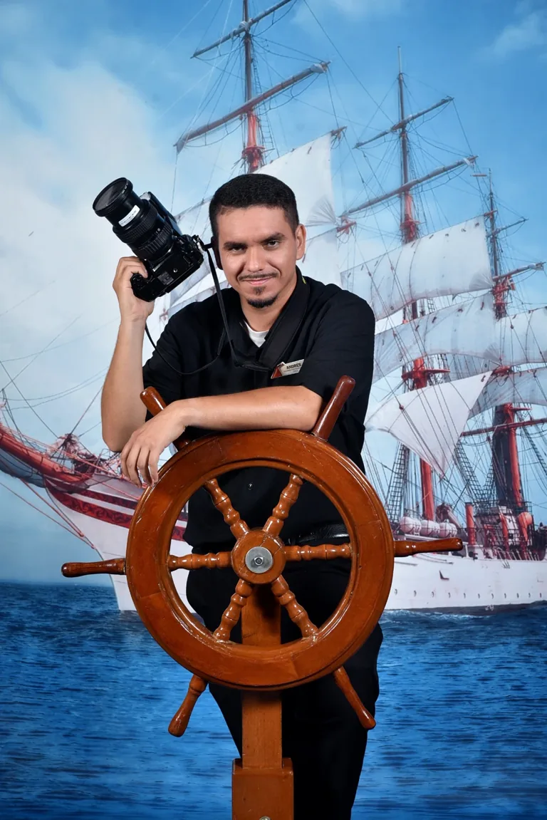 Andrés holding his camera beside a ship’s wheel
