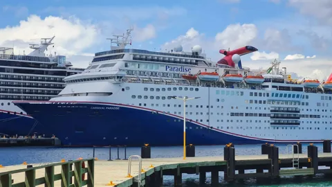 Carnival Paradise docked beside a tropical waterfront