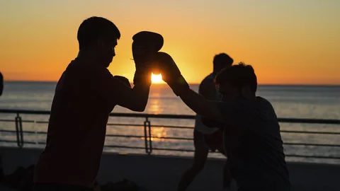 People raising their drinks on deck, silhouetted against the sunset