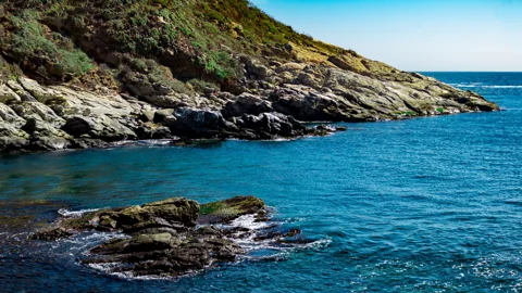 A rocky coastline beside clear blue water